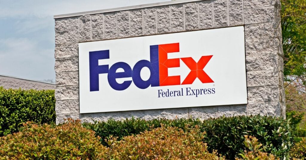 FedEx Logo with white background posted on an outside brick wall.