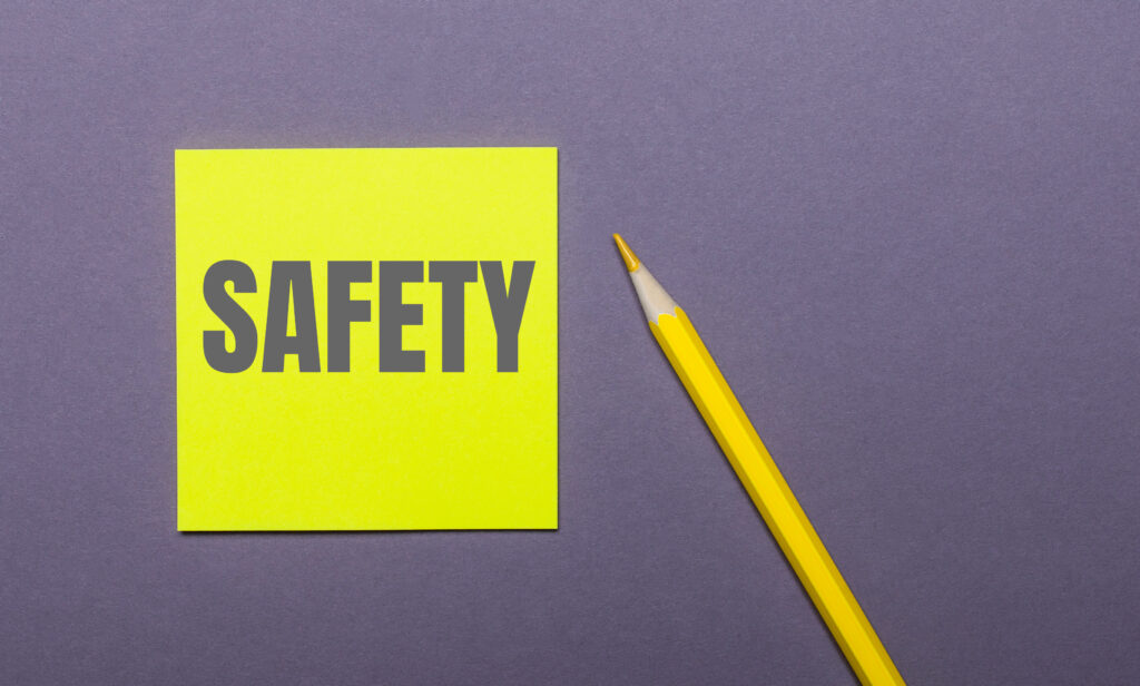 safety word written on a yellow notepad with a pencil on the side and a grey background