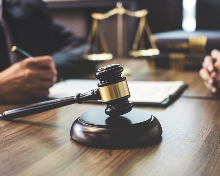 photo of a black gavel with gold accent on a table in a courtroom to symbolize trademark logo