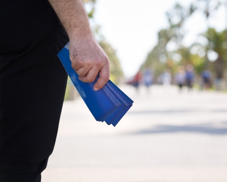 blue flyers holding by a man wearing pants on the street.