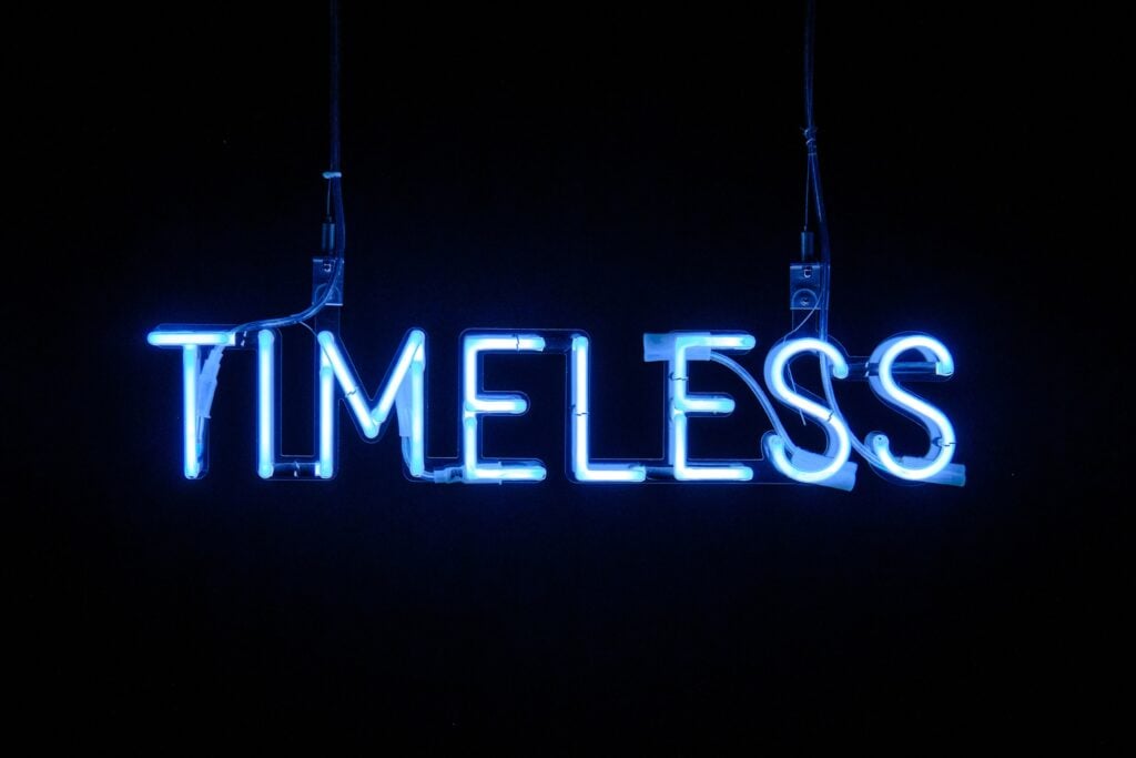 Neon light signage with the word "timeless" on a dark background.