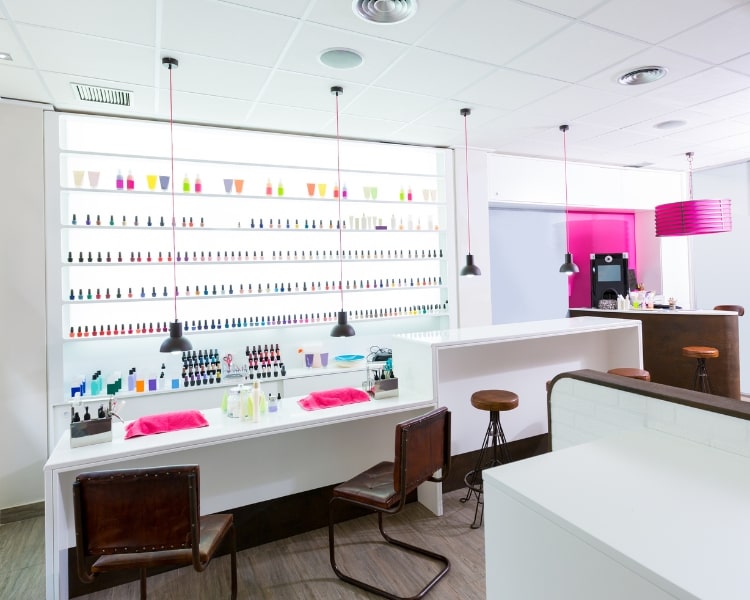 A photo of the inside of a nail store, with different types and colors of nail polish, is displayed on a wall shelf.