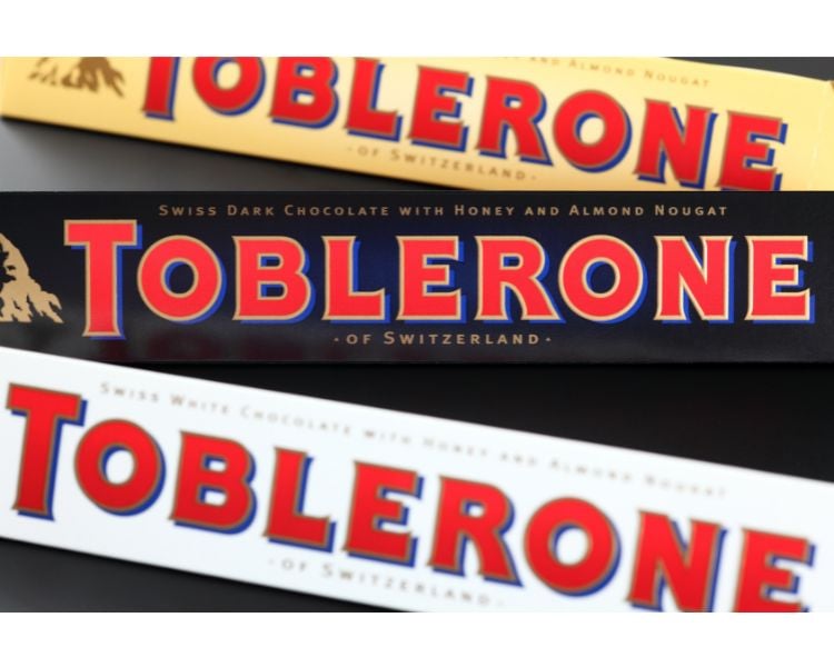 A photo of three Toblerone bar chocolates in three different colors: yellow, black, and white.