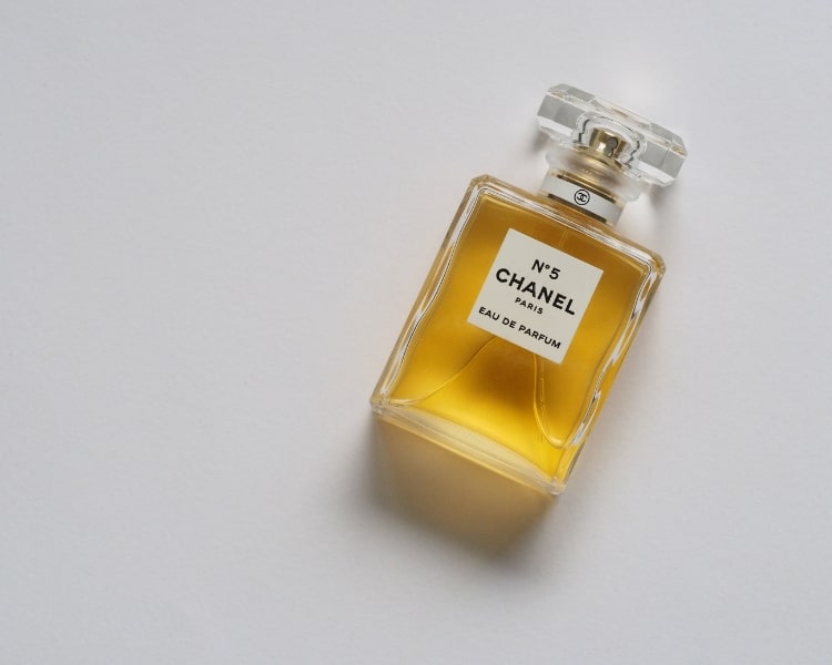 A small bottle of an N5 perfume from the French luxury fashion brand Chanel is lying on a white flooring.