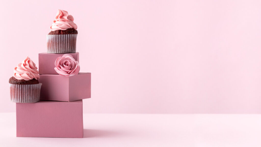 all pink elements on the picture with pink boxes, pick cupcakes, pink flower, and a pink background