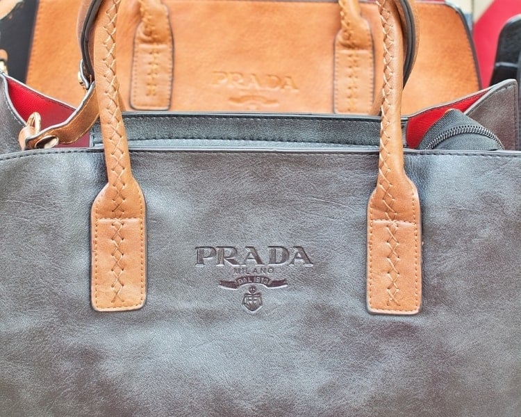 The logo design of the Italian luxury fashion brand Prada is engraved on two of its bag products.
