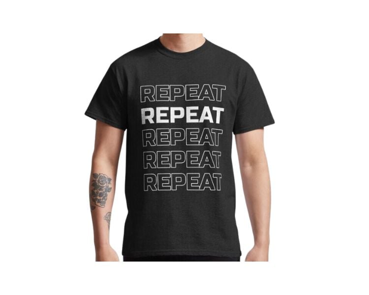 A male clothing model with a tattoo is wearing a black shirt with the word repeat written five times.