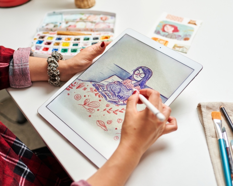 A woman wearing red flannels is sketching a woman wearing an eyeglass using a tablet and stylus pen.