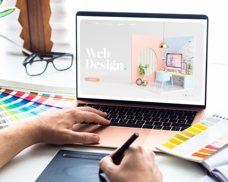 web designer designing a website with a stylus pen and tab at the table as one of the graphic design jobs