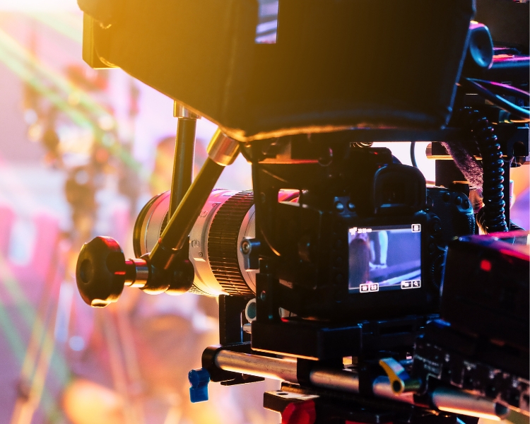 A photograph capturing the rear view of large, professional video cameras at an event or show.