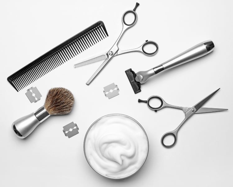 some barbershop tools laid in a table such as scissors, comb, razor, and blade