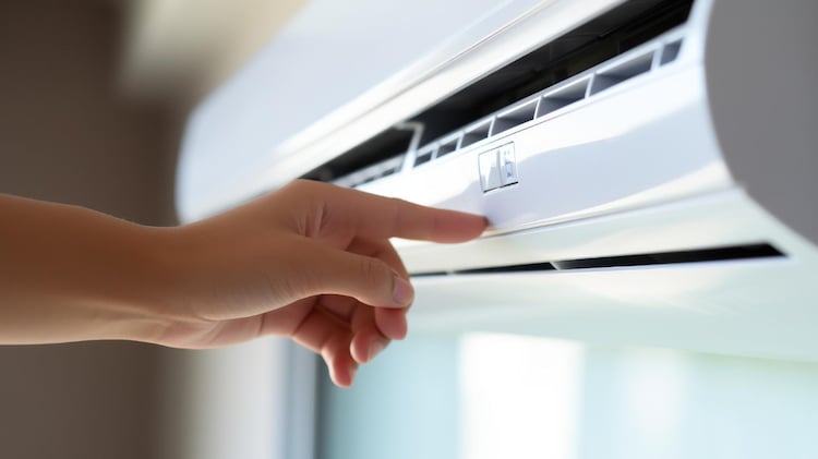 a hand is turning on the air condityional with its button