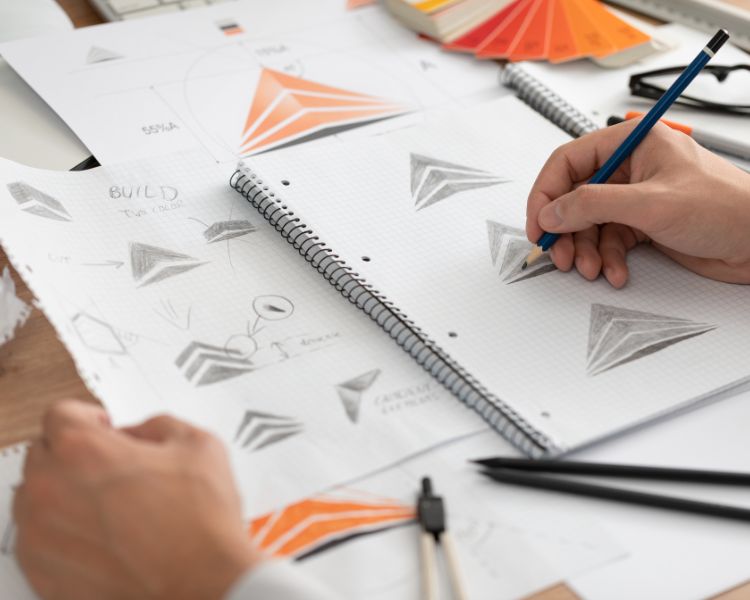 logo design with a pencil in a hand drawing on a notebook