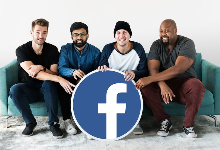 Facebook employees holding a Facebook signage sitting on a sofa