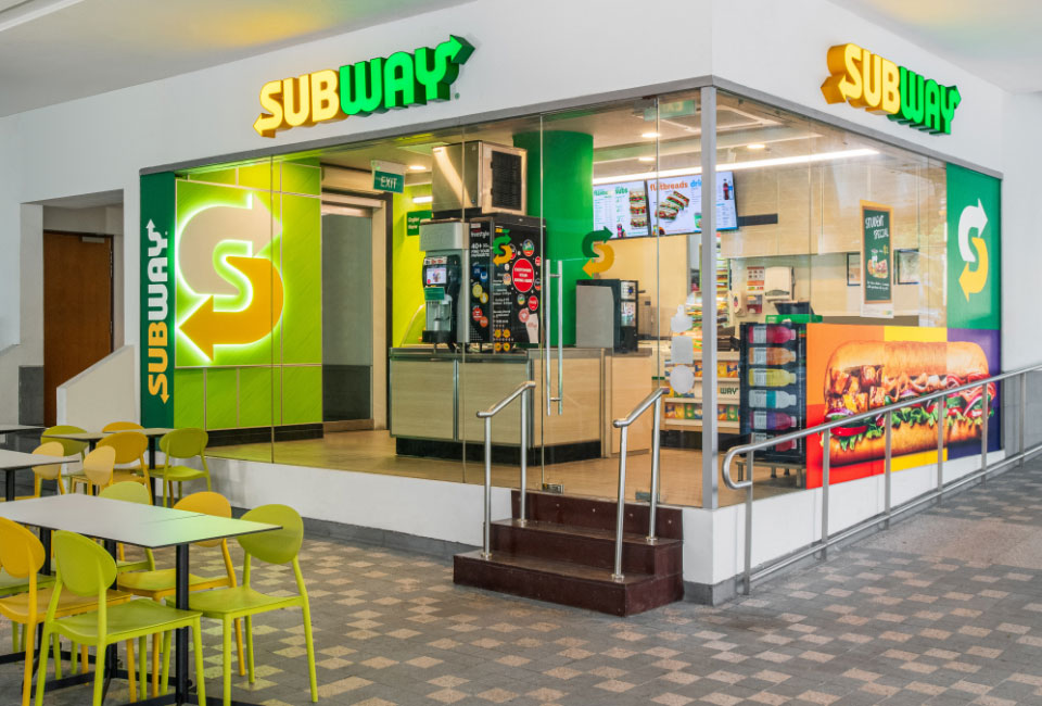 subway store with logos, food product, and green chairs