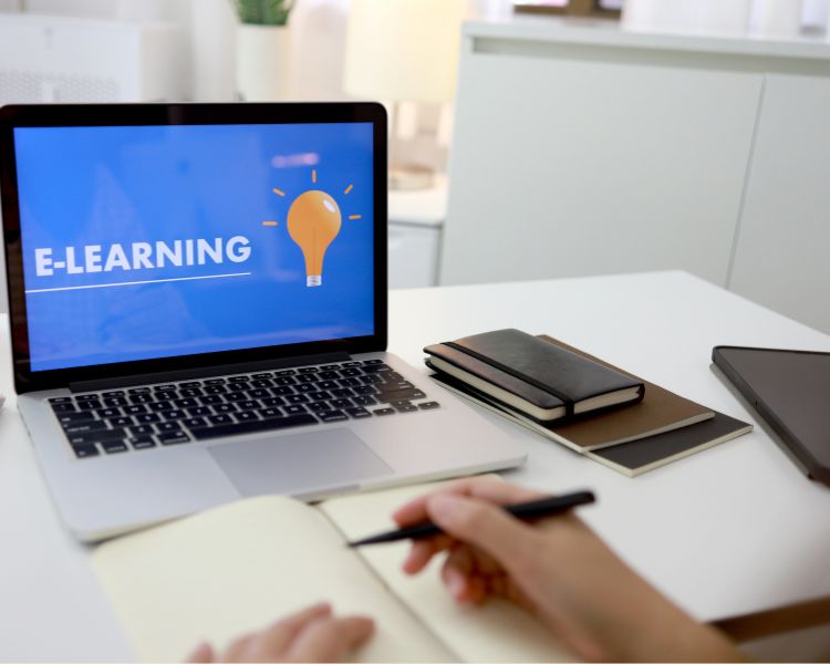 Laptop and notebooks with screen saying E-learning