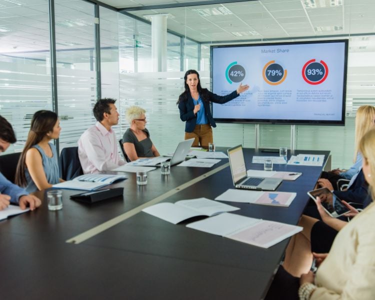 People meeting and listening to a person talking about a company's market share